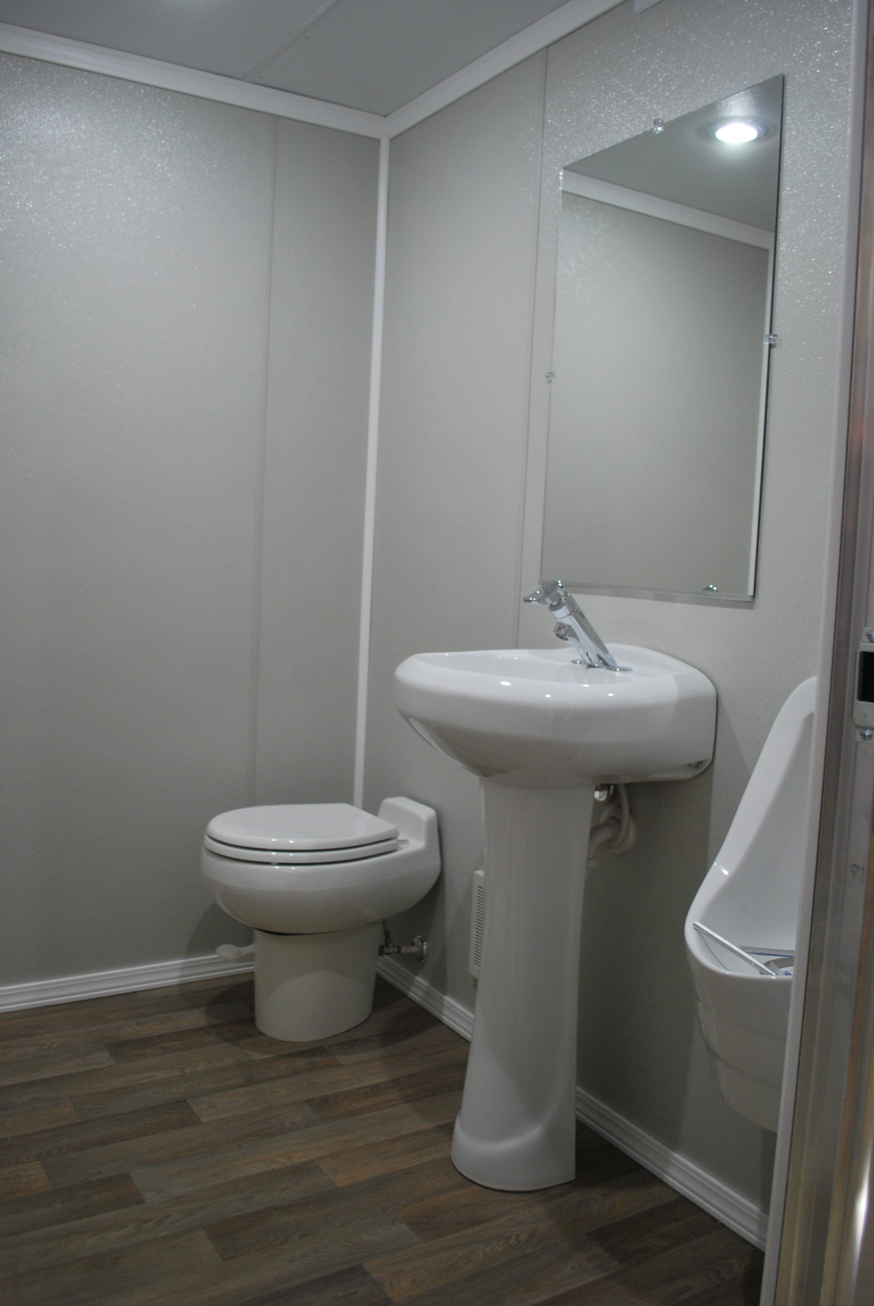 Restroom with toilet, pedestal sink and urinal inside an NRT restroom trailer