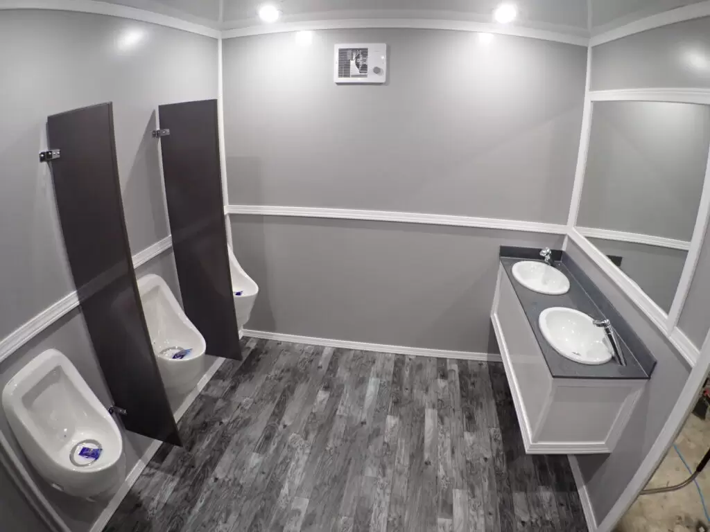 Standard men's side of an NRT multi-stall restroom trailer with urinals and a double vanity
