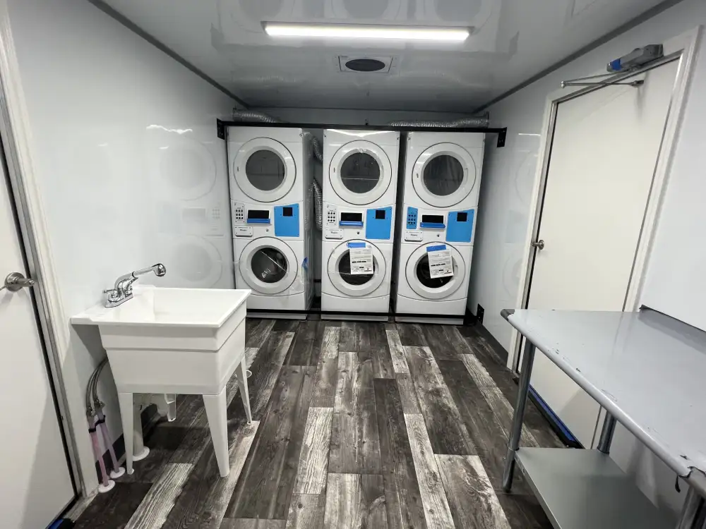 Interior of an NRT mobile laundry trailer with commercial washers and dryers