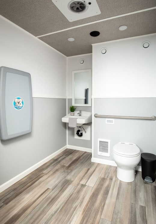 Accessible restroom interior with a grab bar beside the toilet, wall-mounted sink and open floor space